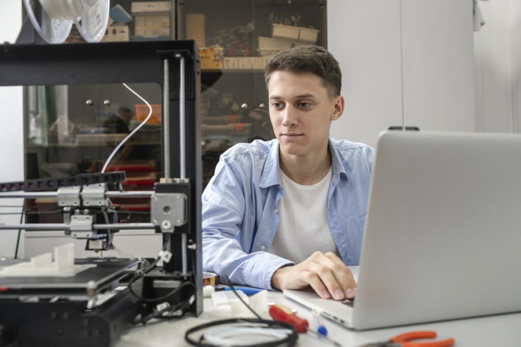 Student setting up 3D printer, using laptop